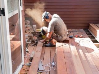 A team of skilled contractors carefully installing Trex composite decking boards on a wooden frame